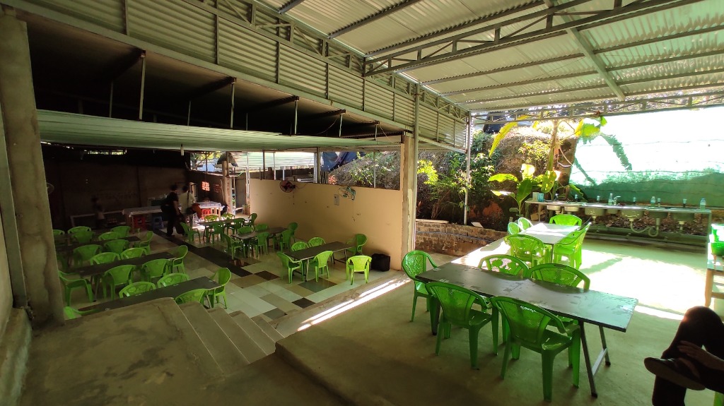Open-air dining hall with green plastic chairs